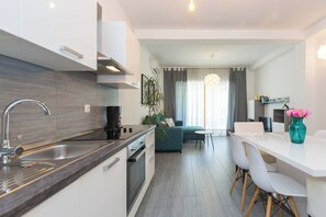 Eine moderne Küche mit Einbauofen, Spüle und Essbereich mit weißem Tisch und Stühlen.