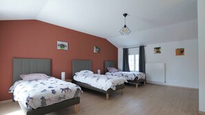 A bedroom with three beds, a radiator, and artwork on the walls.