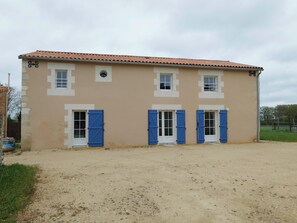 A two-story building with a beige facade, white window frames, and blue shutters.