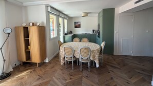 Ein Essbereich mit einem runden Tisch, vier Stühlen, einem Holzschrank und einer Küche im Hintergrund.