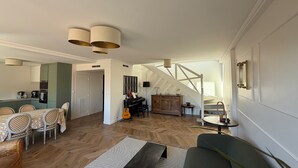 Ein großzügiger Wohnbereich mit Essplatz, einer Couch, einer Treppe und einer Küche im Hintergrund.