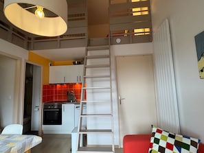 A compact living space with a kitchen, a staircase, and a dining area. - Renovated and Bright Apartment - Direct Sea Access (Cabourg)
