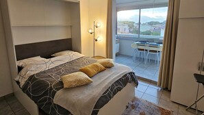 A bedroom with a bed, a desk, and a view of the city. - AC Studio with Parking in Sanary-sur-Mer (Sanary-sur-Mer)