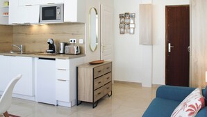Un espacio habitable compacto con kitchenette, comedor y zona de estar.