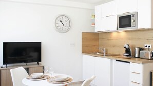 Una cocina moderna con armarios blancos, un microondas, un fregadero y un comedor con mesa y sillas.