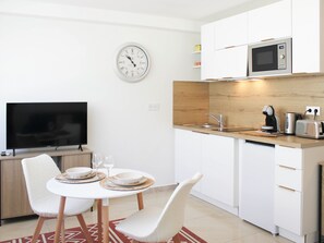 Eine moderne Küche mit weißen Schränken, einer Mikrowelle, einem Spülbecken und einem Essbereich mit Tisch und Stühlen.