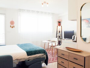 Ein Hotelzimmer mit Bett, Nachttisch, Schreibtisch, Stuhl, Kleiderschrank, Spiegel und einem Fenster mit Vorhängen.