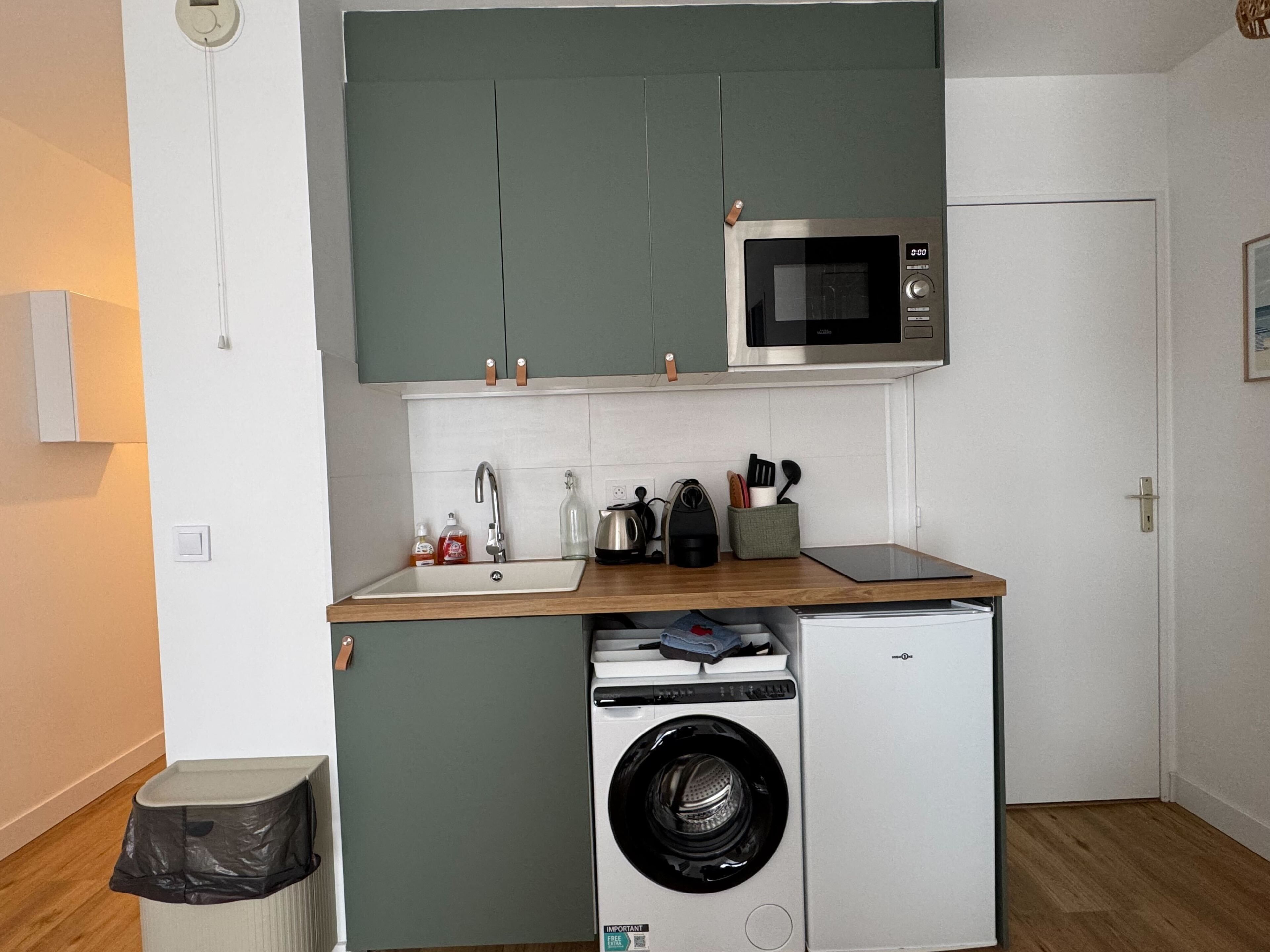 Une cuisine compacte équipée d’un four à micro-ondes, d’un évier et d’un lave-linge.