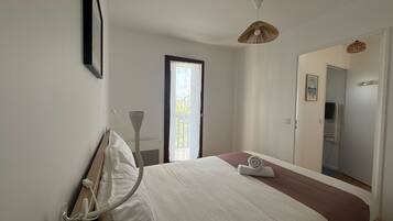 Une chambre à coucher avec un lit, une porte, une fenêtre et un luminaire suspendu.