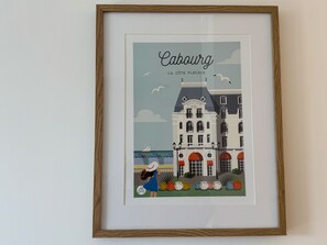 A framed illustration of a building labeled 'Cabourg - La Côte Fleurie' with a grand hotel sign, a sailboat, and a person with a suitcase. - Renovated apt with view & parking in Cabourg (Cabourg)