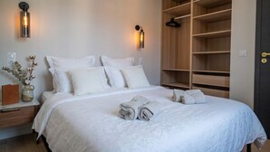 Ein Schlafzimmer mit einem großen Bett, Nachttischen, einem Kleiderschrank und Wandleuchten.