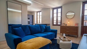Ein modernes Wohnzimmer mit einem blauen Sofa, einer gelben Decke, einem Holzkleiderschrank und einem Spiegel.