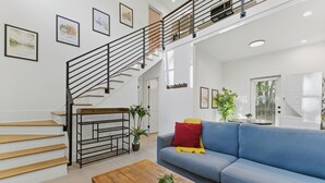 Un salon moderne avec un escalier, un canapé, une table basse et une plante.