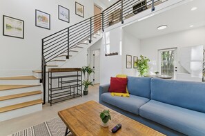 A modern living room with a staircase, a sofa, a coffee table, and a plant. - Private 2BR Brand New House w/Parking (Atlanta)