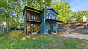 Une maison à deux étages avec un balcon, une véranda et un mur en pierre.