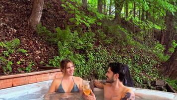 A couple in a hot tub surrounded by lush greenery.