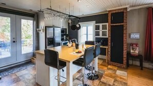 A modern kitchen with a central island, bar stools, and a hanging pot rack.