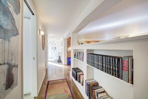 Un couloir avec une bibliothèque, un tapis et un tableau accroché au mur.