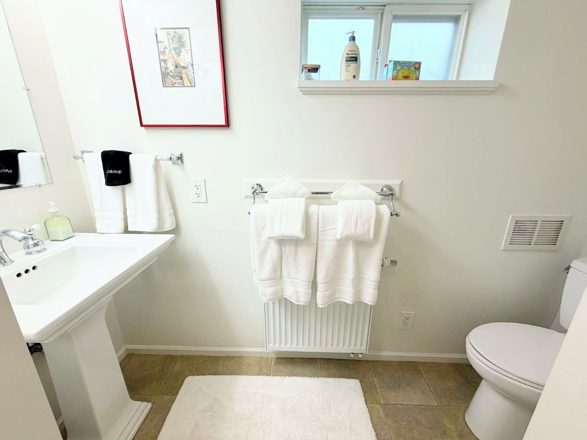 A bathroom with a white sink, mirror, and towel rack.