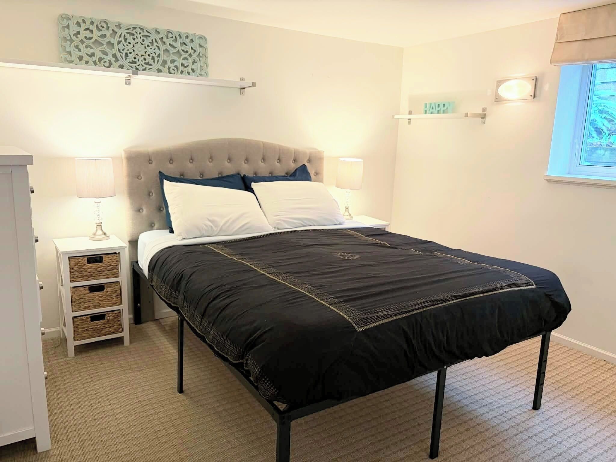 A bedroom with a bed, bedside tables, a wardrobe, and decorative wall art.