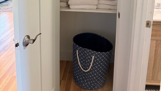 Un placard blanc avec des étagères où sont rangées des serviettes et des couvertures pliées.
