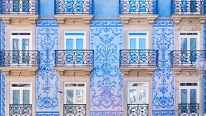 Facciata di un edificio con piastrelle a motivi blu e bianchi, numerosi balconi con ringhiere in ferro battuto e finestre con cornici bianche.