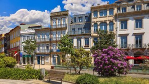 A row of multi-story buildings with balconies, a bench, and a tree with purple flowers. - Oporto Tiles Mezzanine by Hopstays | Marquês (Porto)