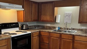A kitchen with wooden cabinets, a white stove, a sink, and a ceiling light. - NEW RENTAL-GREAT RATES! Peaceful 2B-1.5B cottage- 0.4 mile to FCF State Park (Pikeville)