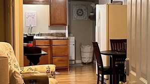 A cozy living room with a sofa, a dining table with chairs, and a kitchen area with cabinets and a refrigerator. - NEW RENTAL-GREAT RATES! Peaceful 2B-1.5B cottage- 0.4 mile to FCF State Park (Pikeville)