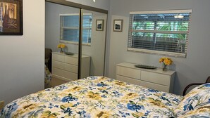 Un dormitorio con cama, cómoda, espejo y ventana con persianas.