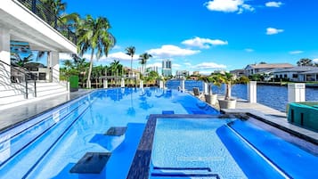 A swimming pool with a clear view of the water, surrounded by palm trees and buildings.