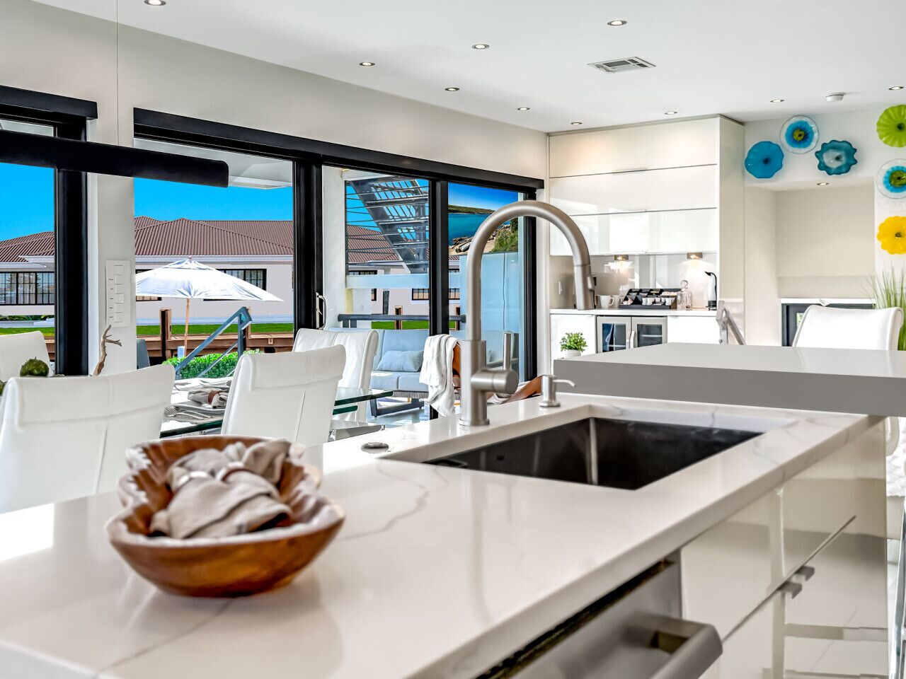 Eine moderne Küche mit einem großen Fenster, weißen Schränken und einer Schüssel auf der Arbeitsplatte.