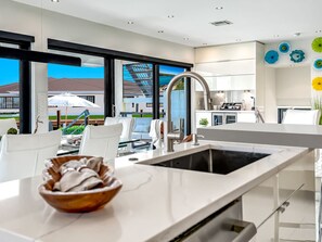 Eine moderne Küche mit einem großen Fenster, weißen Schränken und einer Schüssel auf der Arbeitsplatte.