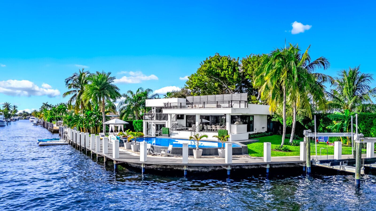 A waterfront property with a pool, dock, and lush greenery.