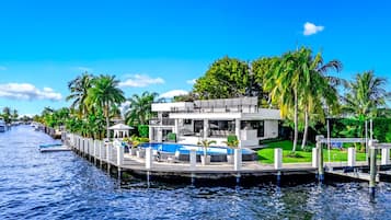 A waterfront property with a pool, dock, and lush greenery.