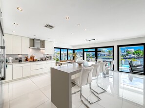 A modern kitchen with a central island, white cabinetry, and a view of a cityscape through large windows.