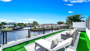 A rooftop deck with a pool, outdoor seating, and a view of a canal.