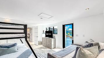 Une chambre moderne avec des lits superposés, un téléviseur et une vue sur une piscine.