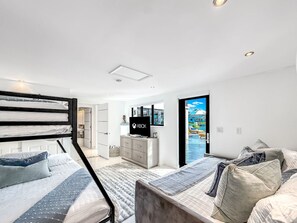 Un dormitorio moderno con literas, televisión y vista a una piscina.