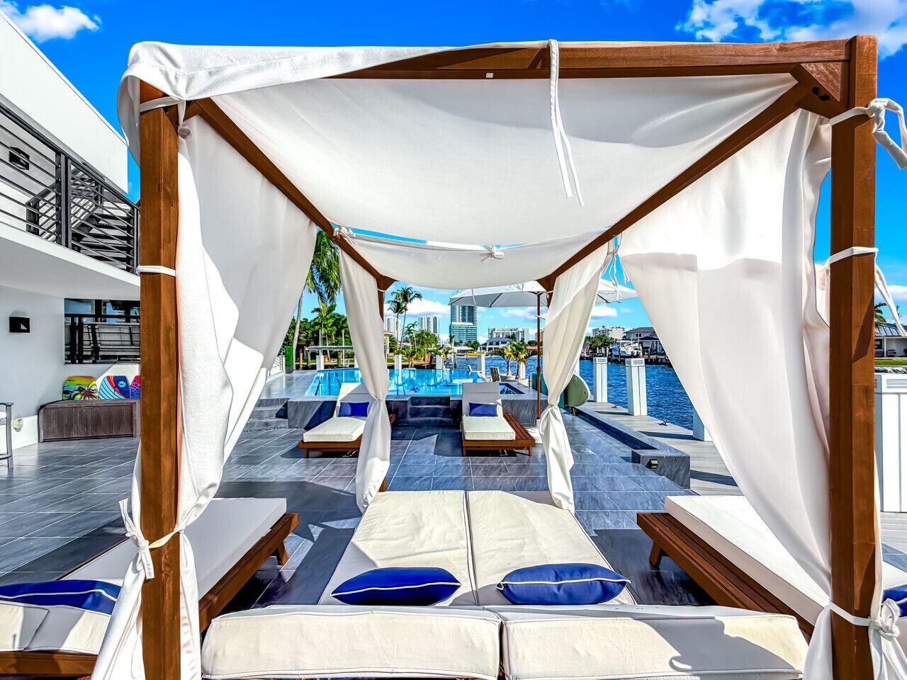 Ein Strandloungebereich mit Baldachin, mehreren Liegestühlen und Blick auf Pool und Meer.
