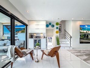 Una sala de estar moderna con un ventanal grande, una zona de comedor y una cocina.
