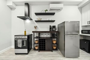 Eine moderne Küche mit Einbauofen, Edelstahl-Kühlschrank und einer schwarzen Kücheninsel mit Regalen.