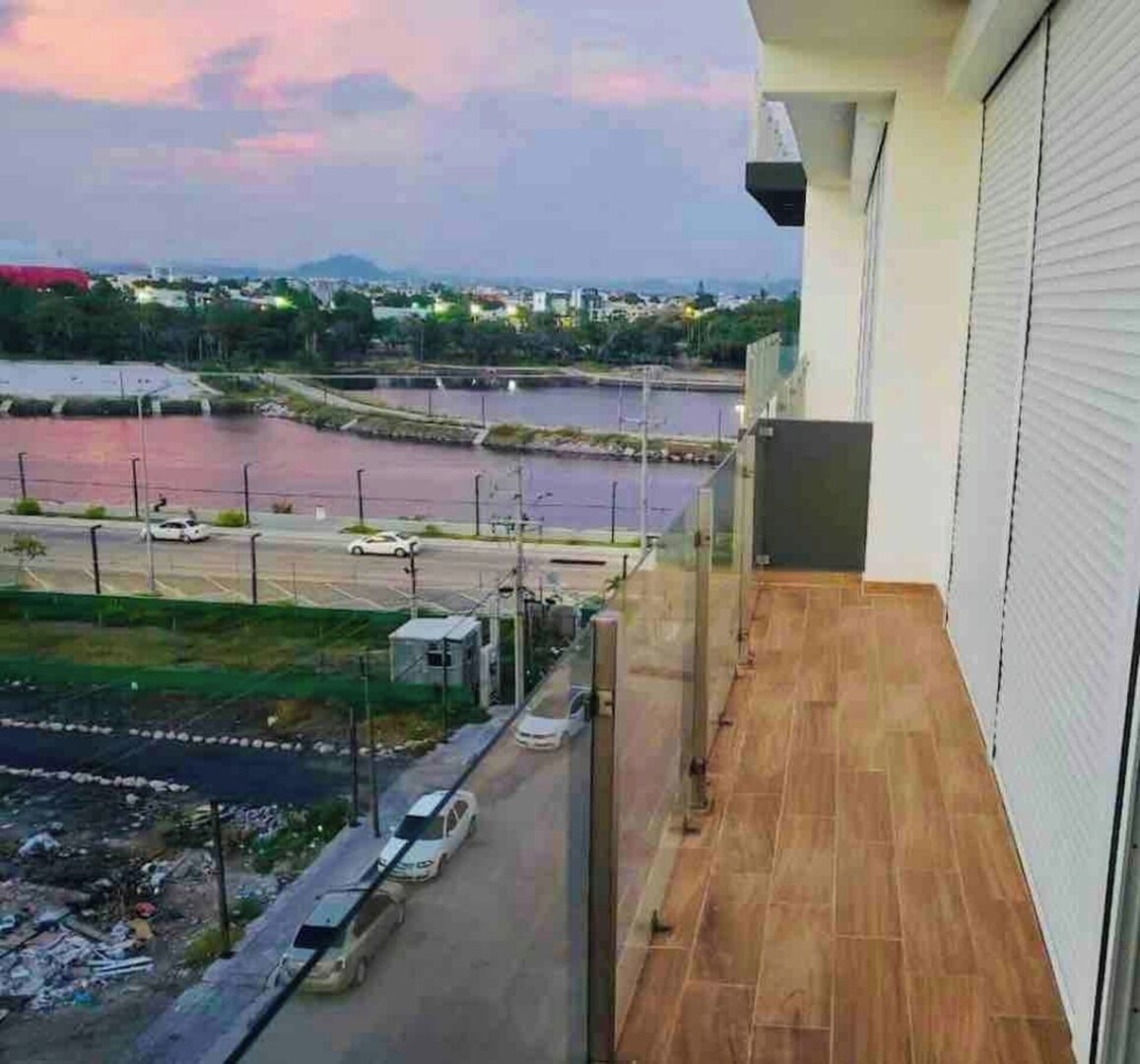 Un balcón con vista a un río, un estacionamiento y edificios a la distancia.