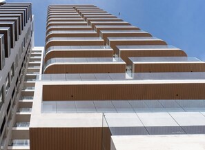 A modern building with a unique stepped facade, large windows, and a clear sky. - Luxury apt on the Malecón with lagoon views (Mazatlan)
