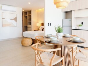 A modern hotel room with a bed, a dining table with chairs, a kitchen area, and a living space. - Luxury apt on the Malecón with lagoon views (Mazatlan)