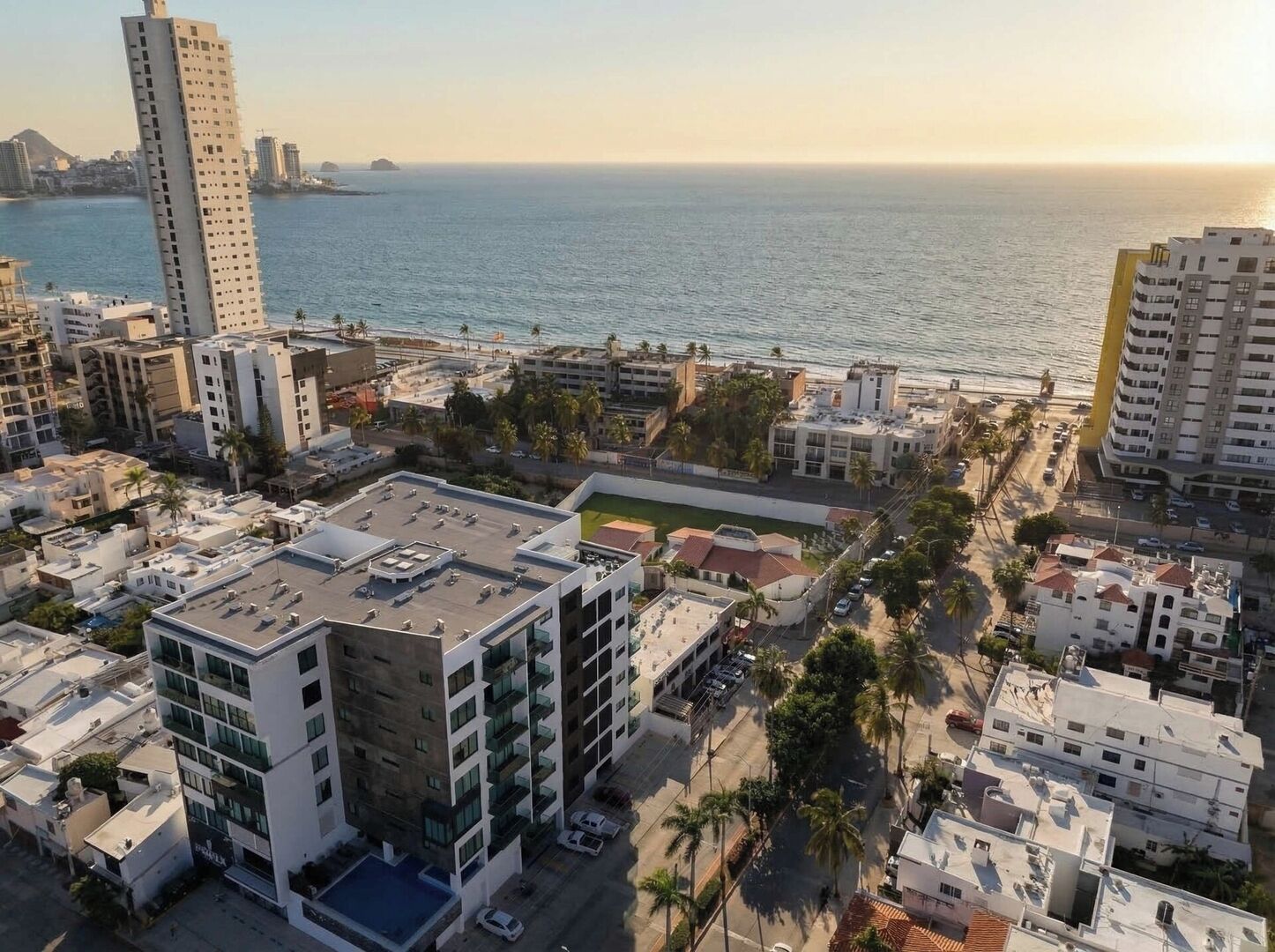 A coastal urban area with high-rise buildings, a beach, and a clear view of the ocean.
