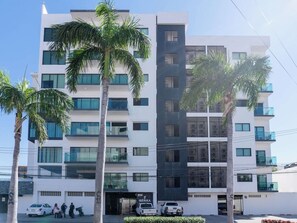 A multi-story building with a modern design, featuring balconies and large windows. - Family apartment with roof and great location (Mazatlan)