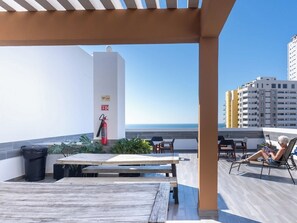 A rooftop terrace with a view of the sea, a fire extinguisher, and a table with chairs. - Family apartment with roof and great location (Mazatlan)