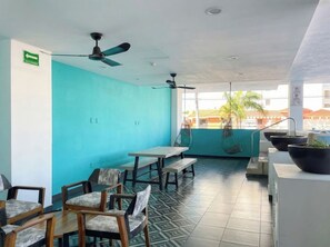 A room with teal walls, ceiling fans, a tiled floor, and a view of palm trees and buildings outside. - Family apartment with roof and great location (Mazatlan)