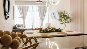 Un comedor moderno con una mesa de mármol, detalles decorativos dorados y vista al salón.